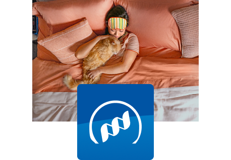 Kissa lepää omistajansa kanssa sängyllä