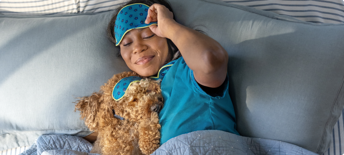 Koira lepää omistajansa kanssa sängyssä